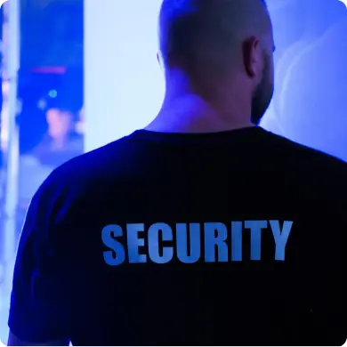 Guardia de seguridad de espaldas con playera distintiva en un evento nocturno